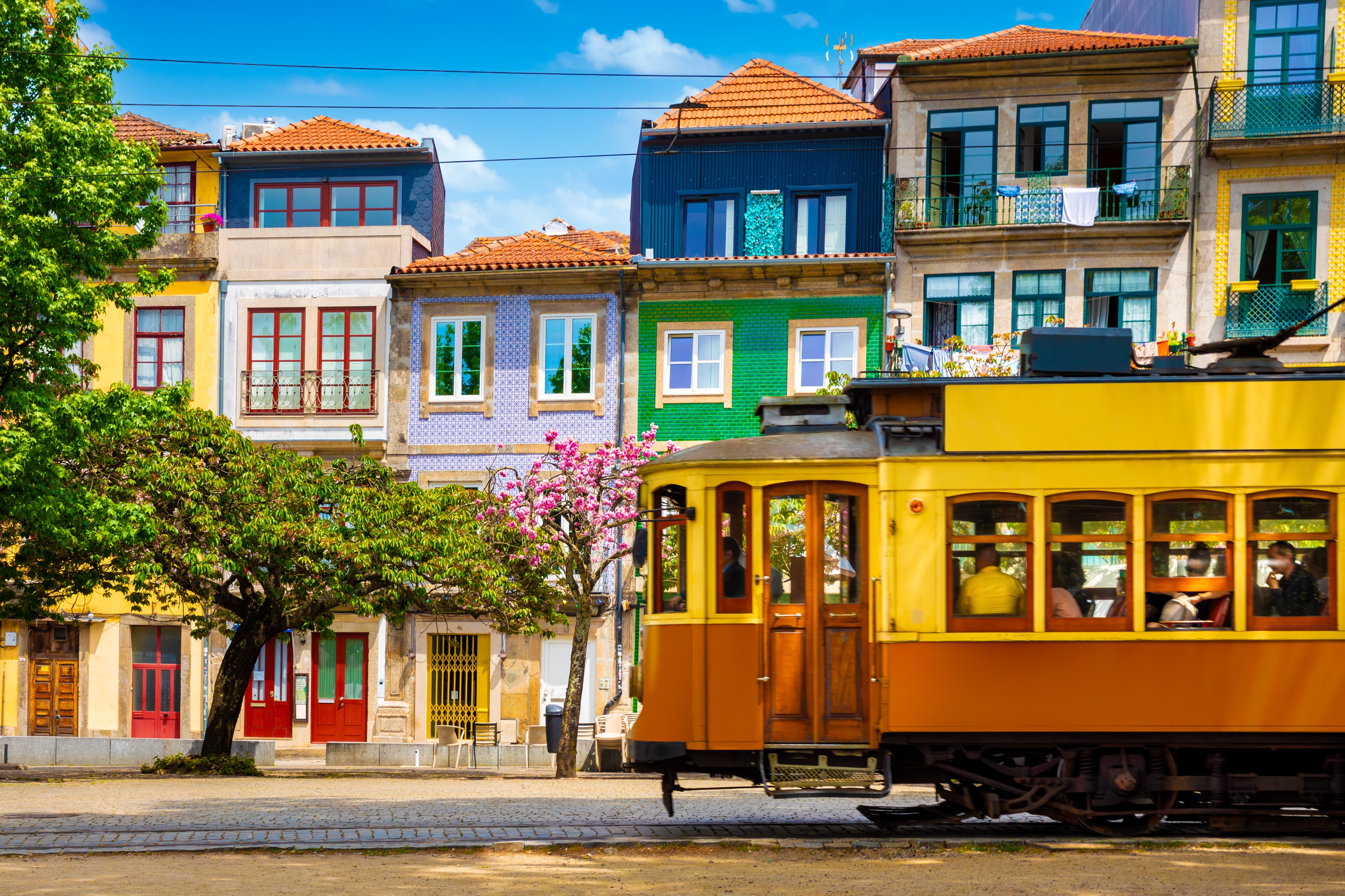 a yellow tram in front of colourful houses in Porto, Portugal